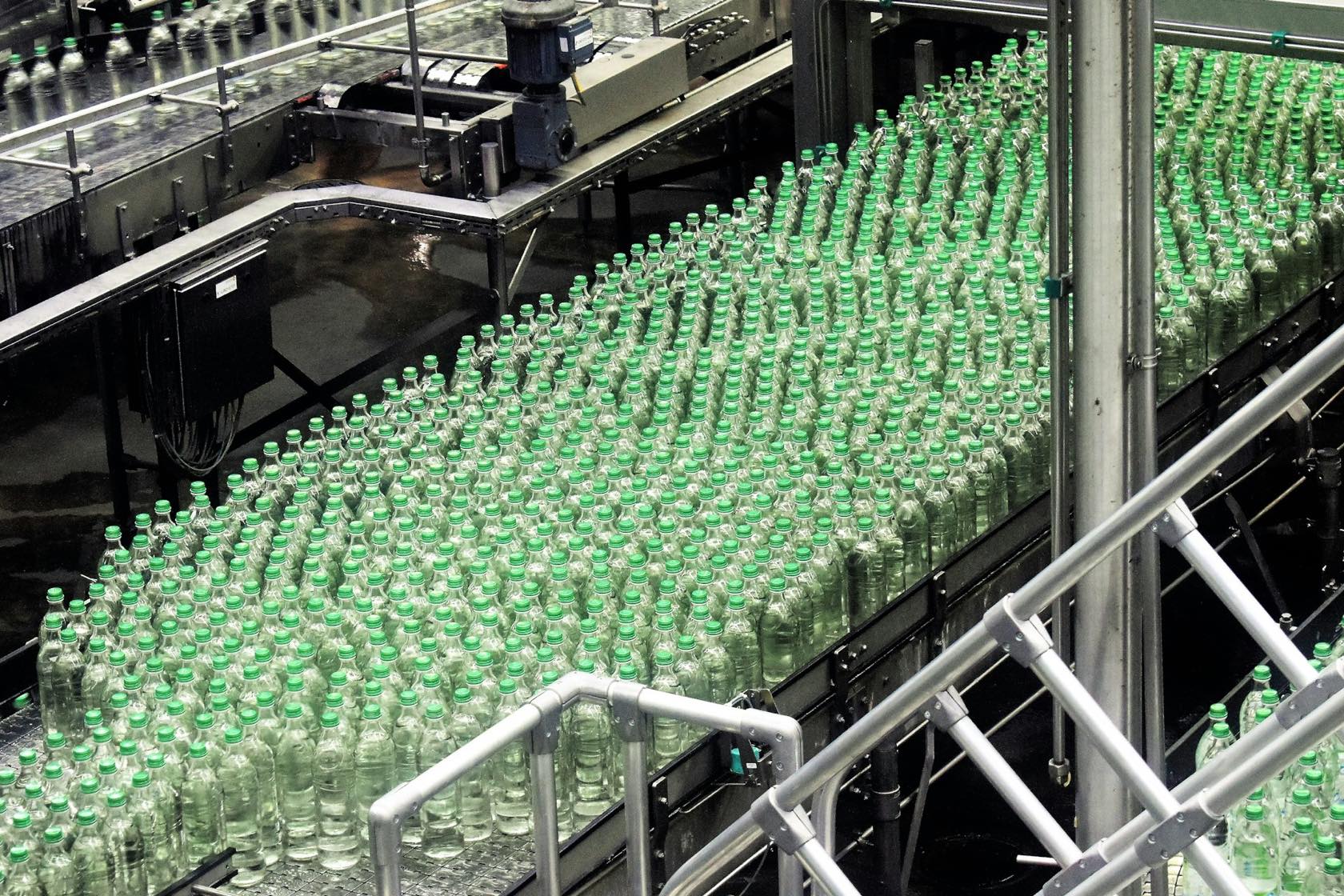 Botellas de vidrio avanzando por una línea de llenado de acero inoxidable